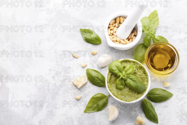 Pesto sauce and ingredients, cheese, basil, garlic, pine nuts, olive oil on grey stone background
