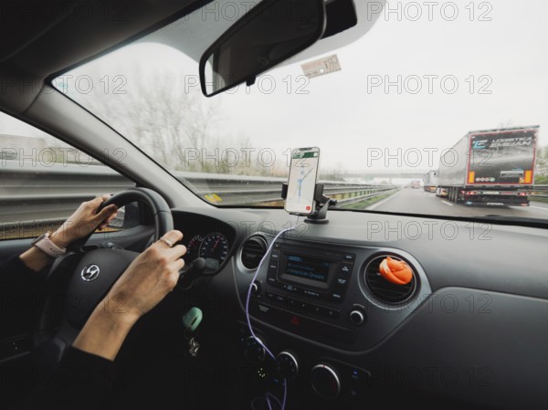Inside view of a car with the driver's hands on the wheel and a mobile navigation system, A1 A8