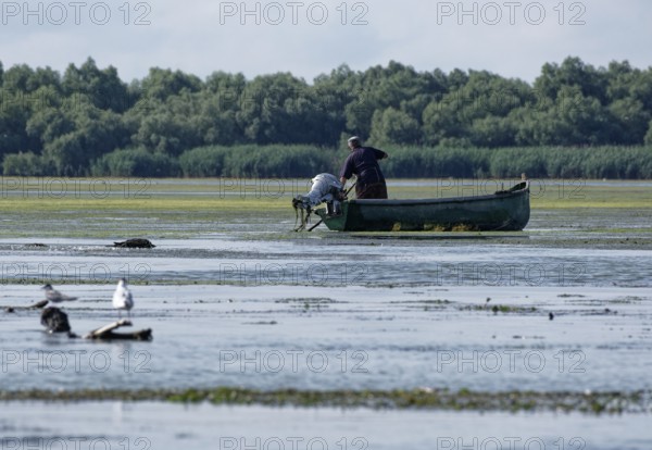 Fishermen in a boat on the water of Lacul Isaccel, a lake in the Danube Delta. UNESCO Danube Delta