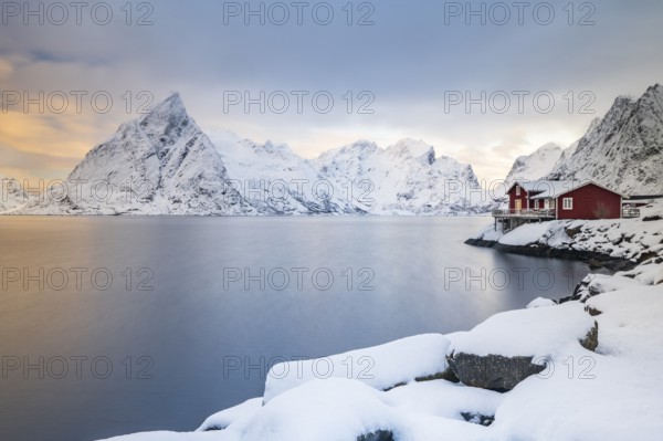 Red huts on the island of Sakrisøy, snow-covered mountains in the background, Sakrisoy, Reine,