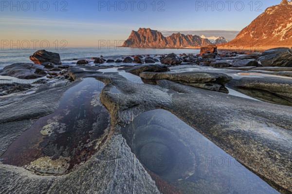 Rocky coast in front of steep mountains in the evening light, winter, the eye, Utakleiv,