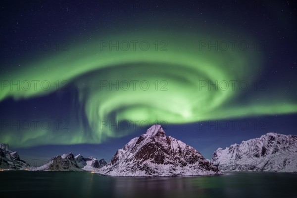 Green northern lights reflected in fjord, steep mountains, aurora borealis, winter, Reine,
