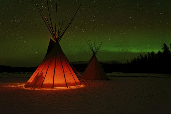 Two tents, tipis, Indian tents, front one illuminated from the inside, in a winter landscape,