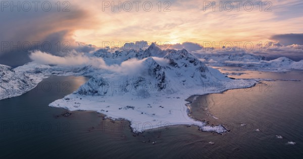 View of Flakstad and Skagsanden beach, snow-covered mountains and fjord at sunset, aerial view,