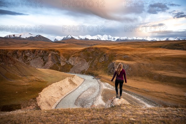Glaciated and snow-capped mountains, Young woman in mountain landscape with yellow grass in the