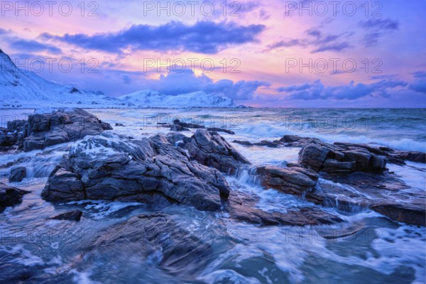 Waves of Norwegian sea on rocky coast in fjord on sunset with sun. Skagsanden beach, Lofoten