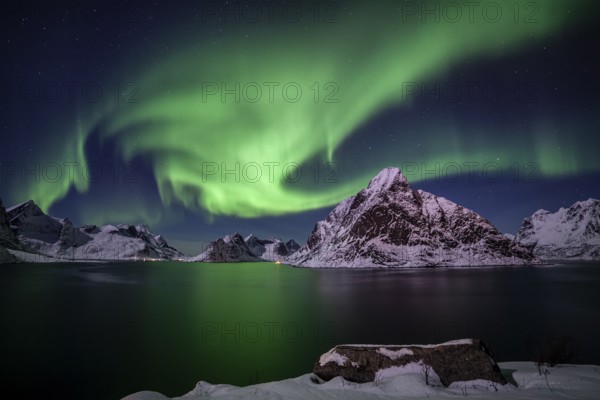 Green northern lights reflected in fjord, steep mountains, aurora borealis, winter, Reine,