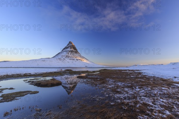 Pointed mountain reflected in fjord at low tide, snow, winter, morning light, Kirkjufell,