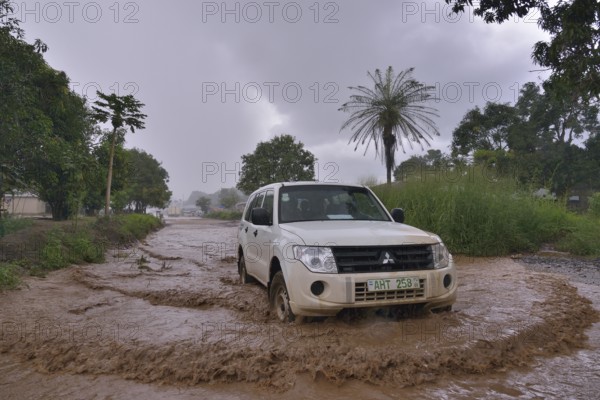 Car driving on a flooded street during the rainy season, near Makeni, Bombali District, Sierra