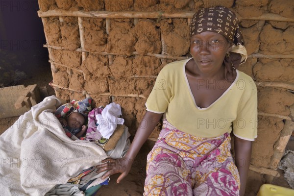 Woman with a child sitting in front of her hut, near Kent, Western Area Region, Sierra Leone,
