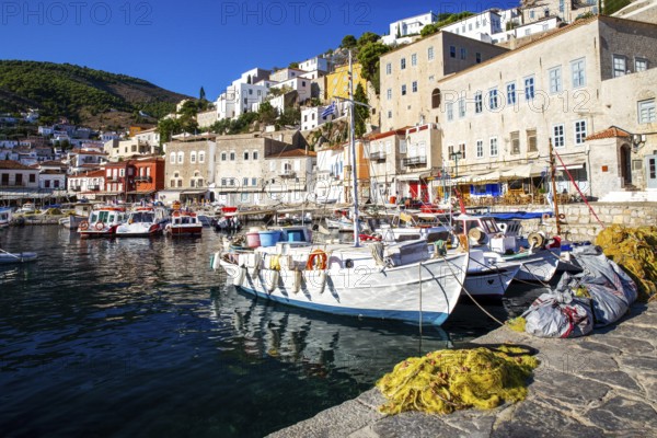 Fishing and recreational boats in harbor of Hydra island. Houses of Hydra town with tiled roofs on