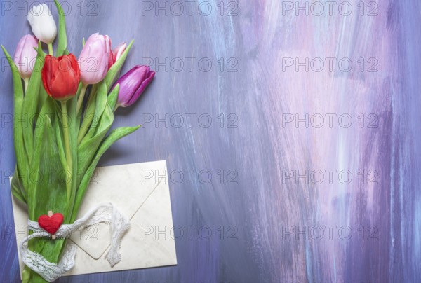 Bouquet of colorful tulips tied with a lace ribbon and a wooden clip with a red heart, and a closed