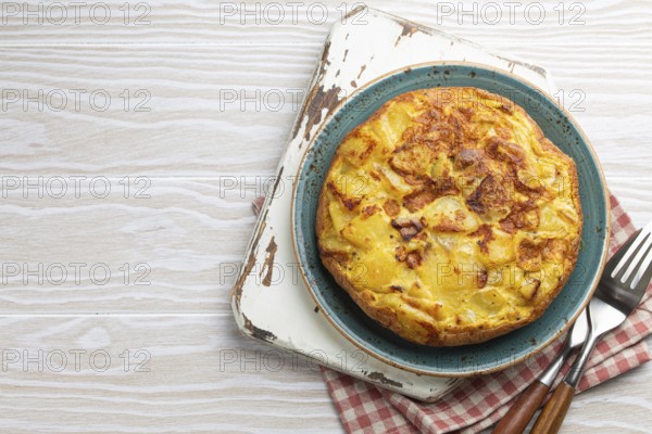 Homemade Spanish tortilla - omelette with potatoes on plate on white wooden rustic background top
