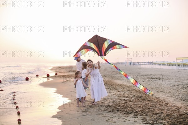 Happy family with parents and kids playing together with snakes on a beach vacation. Summer