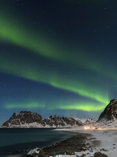 Spectacular dancing green strong northern lights over the famous round boulder beach near Uttakleiv