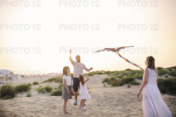 Happy family with parents and kids playing together with snakes on a beach vacation. Summer