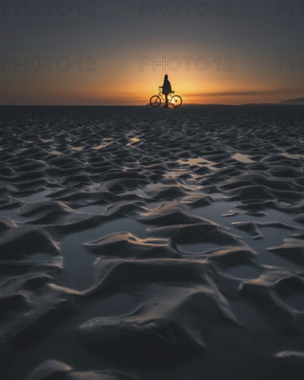 Silhouette of a person with a bicycle on a beach during a picturesque sunset, Tofino, BC, Canada,