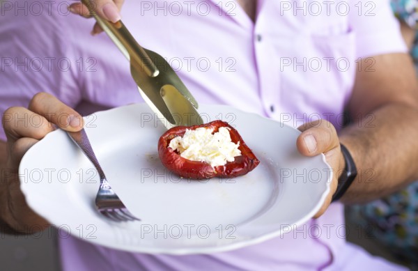Baked red-colored bell peppers stuffed with herbs and cheese on a dish on summer outdoors party.