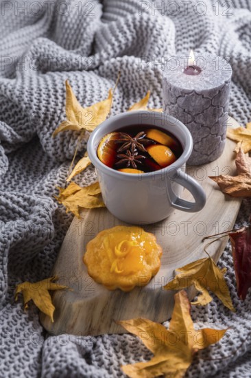 Cosy and soft winter background, with mulled wine, knitted blanket and candle with lemon cake on
