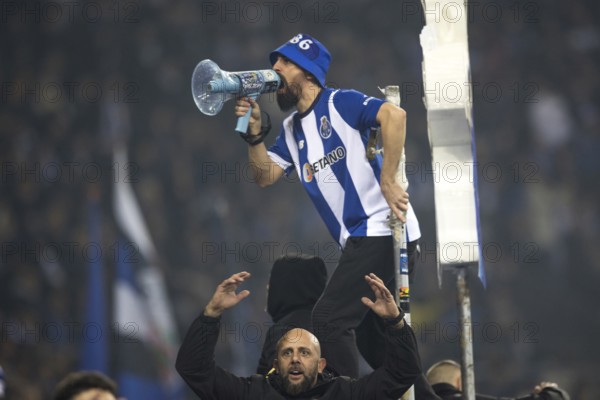 Football match, a fan of FC Porto with jersey on the fence shouting with a megaphone, another fan