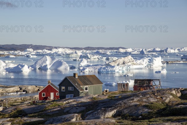 Rodebay, Greenland, July 09, 2018: Colorful wooden houses with icebergs in the background. Rodebay,