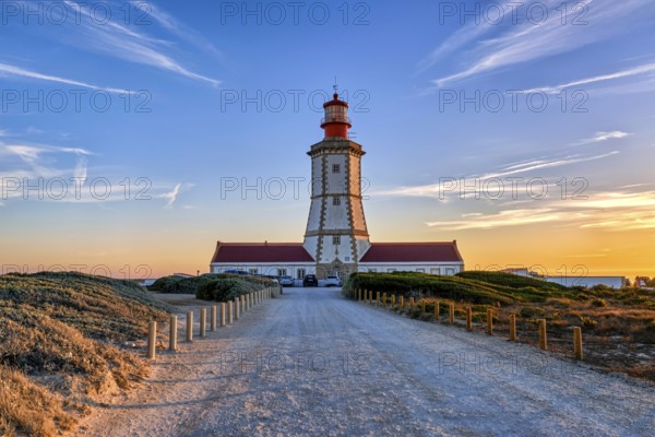 Beautiful of coastal lighthouse in warm colors of sunset, a clear path leading to it. Clear blue
