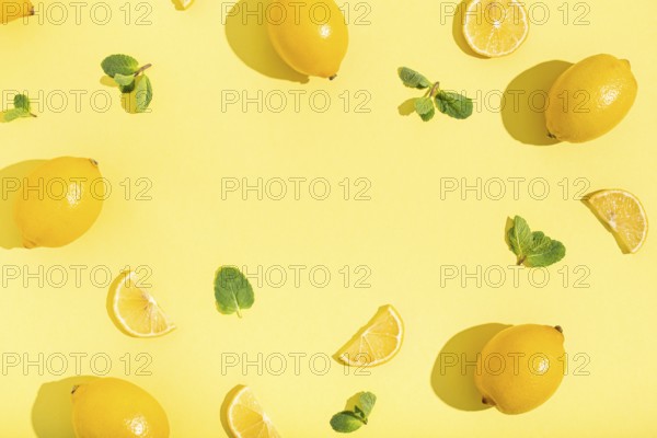 Fresh yellow lemons with mint on minimal beige yellow background on bright sun light with hard