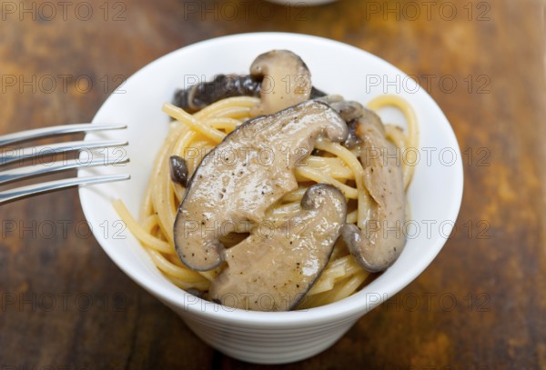 Italian spaghetti pasta and fresh wild mushrooms on rustic wood table