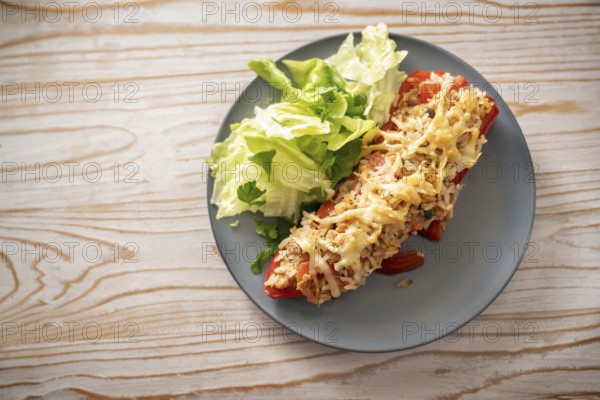 Pointed red bell pepper baked with rice, tuna and cheese, lettuce salad with parsley garnish on a