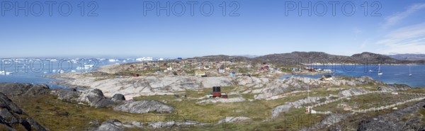 Rodebay, Greenland, July 09, 2018: Colorful wooden houses with icebergs in the background. Rodebay,