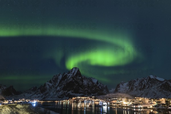 Dancing green polar lights over the village Reine on the Lofoten islands in Norway at night in