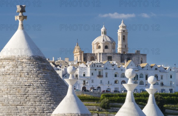 View through trulli, round conical houses, to Locorotondo with the neoclassical church San Giorgio