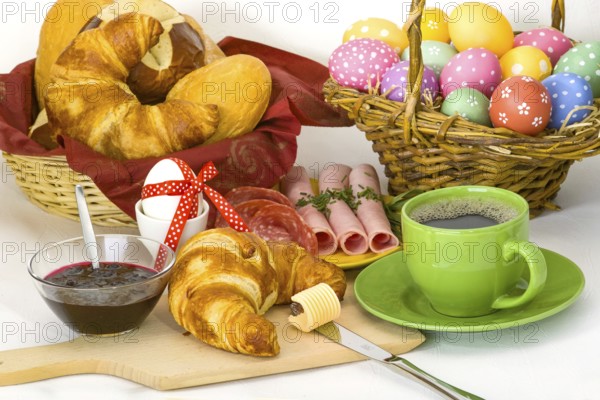 Colourful Easter breakfast with Easter eggs, coffee, croissant, ham and jam