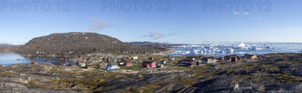 Rodebay, Greenland, July 09, 2018: Colorful wooden houses with icebergs in the background. Rodebay,