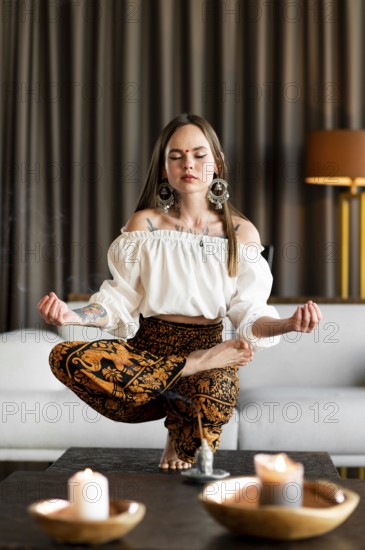 Full shot woman meditating inside