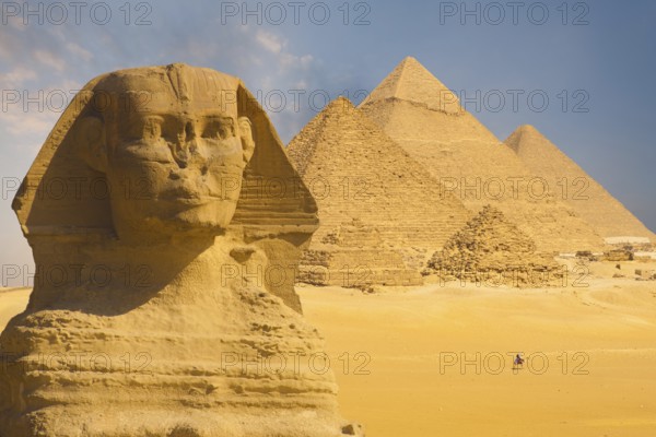 A closeup of the face of the Great Sphinx with a set of pyramids in the background on a beautiful