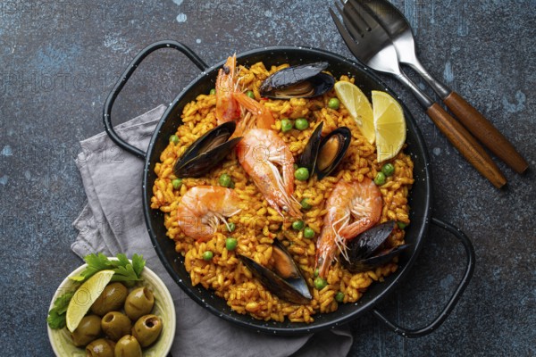 Classic dish of Spain, seafood paella in traditional pan on rustic blue concrete background top