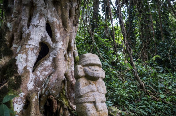 San Agustin, Colombia: A mysterious statue of a male person stands in the rainforest next to an old