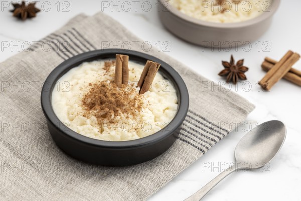 Creamy rice pudding with cinnamon in bowl on white marble table. Typical Spanish dessert