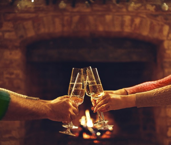 People clinking champagne glasses while gathering around fireplace in country house, cropped shot.
