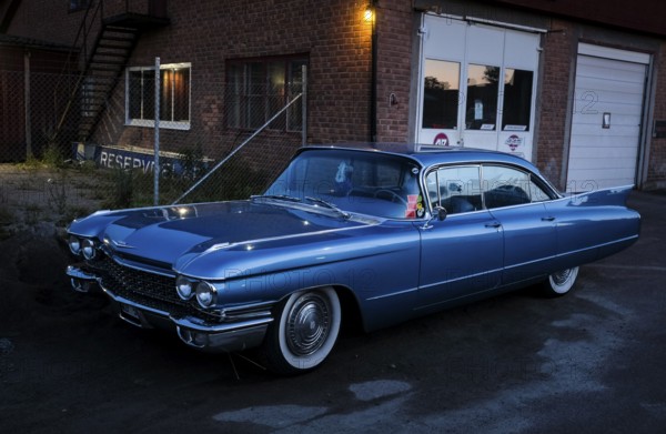 American classic car, blue Cadillac in front of red brick building, industrial area, night shot,