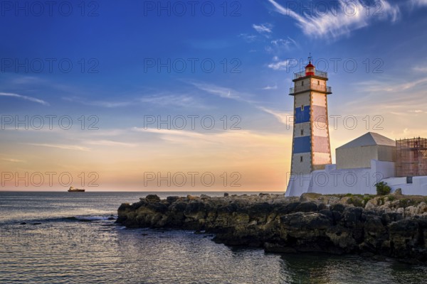 Dramatic sunset on sea shore and Santa Marta lighthouse in Cascais, Portugal. Colorful sky, clouds,