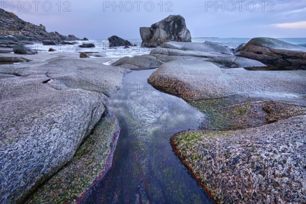 Rocks on beach of fjord of Norwegian sea in winteron sunset. Utakliev beach, Lofoten islands,
