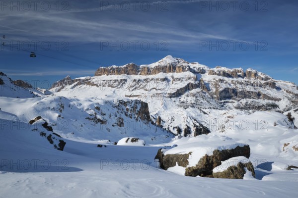 View of a ski resort piste with people skiing in Dolomites in Italy with cable car ski lift. Ski