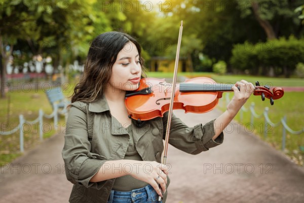Woman playing the violin in the street. Close up of violinist girl playing in a park. Artist woman