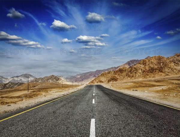 Travel forward concept background, road in Himalayas with mountains and dramatic clouds. Ladakh,