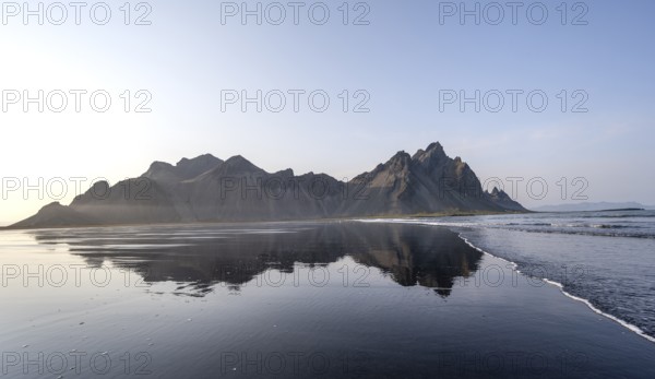 Black lava beach, sandy beach and sea, mountains Klifatindur reflected in the water, Eystrahorn and
