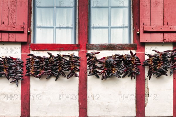 Chilli peppers, Piment dEspelette hanging to dry on facade, typical window with red shutters,