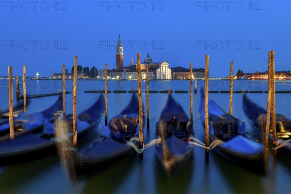 Venetian gondolas near St. Mark's Square in the evening light, blue hour, in the background the