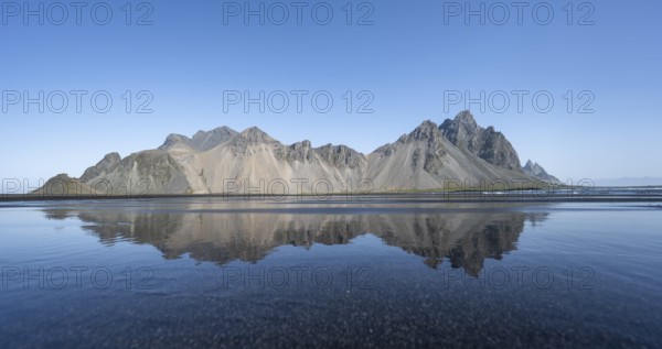 Black lava beach, sandy beach and sea, mountains Klifatindur reflected in the water, Eystrahorn and